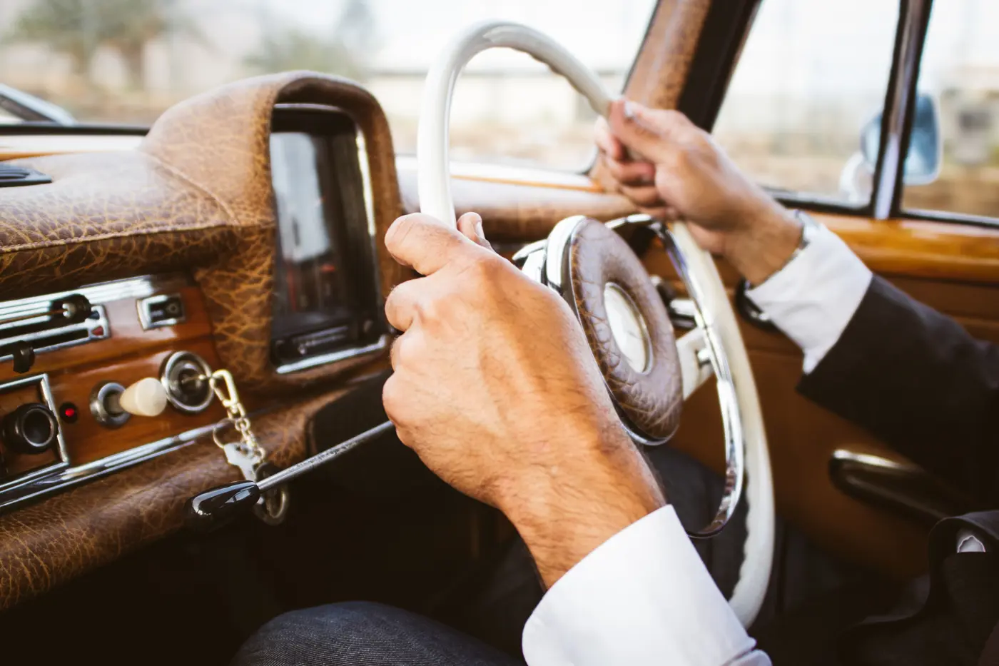 A man in a suit driving a classic car
