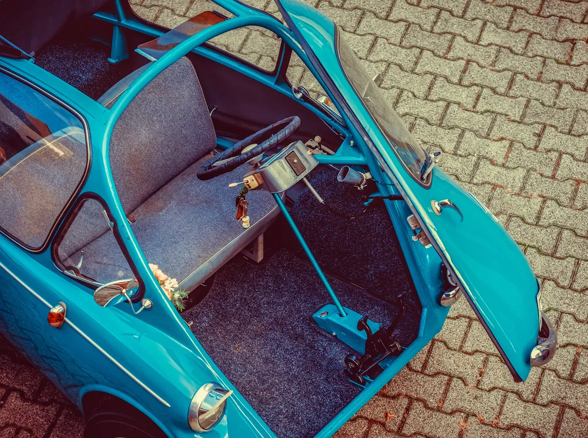 An Isetta bubble car parked on a pavement with its door open