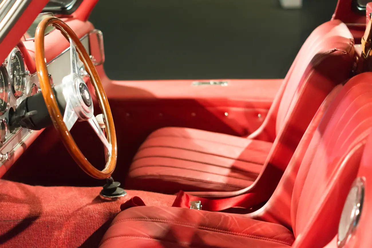 A classic car's red interior with leather seats and dashboard