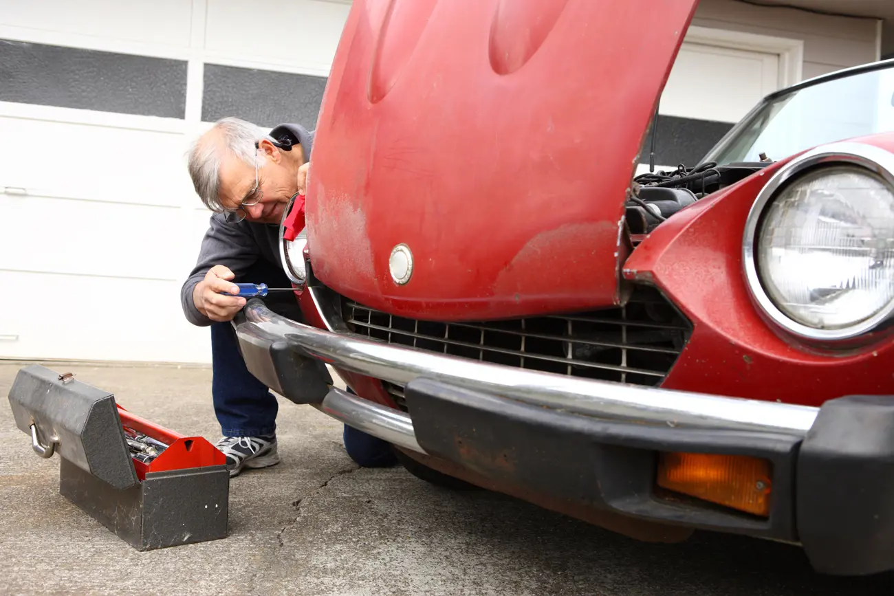 A man using tools to work on restoring his classic car