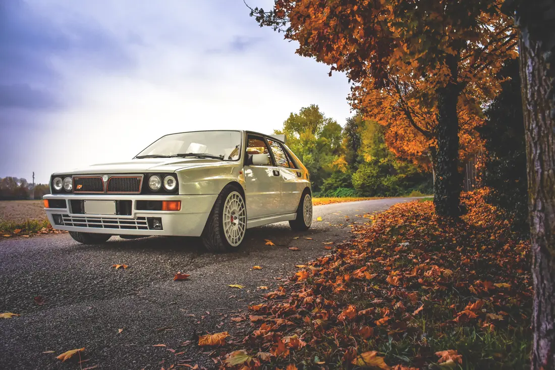 A classic rally car parked on a leafy road