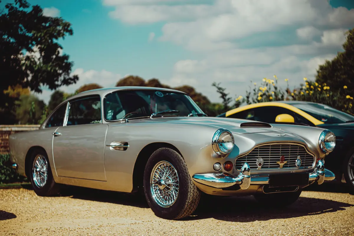 An Aston Martin DB5 parked on a gravel driveway