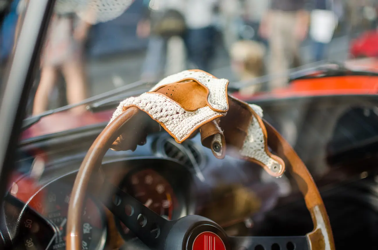 A pair of leaving driving gloves draped over the wooden steering wheel of a classic car