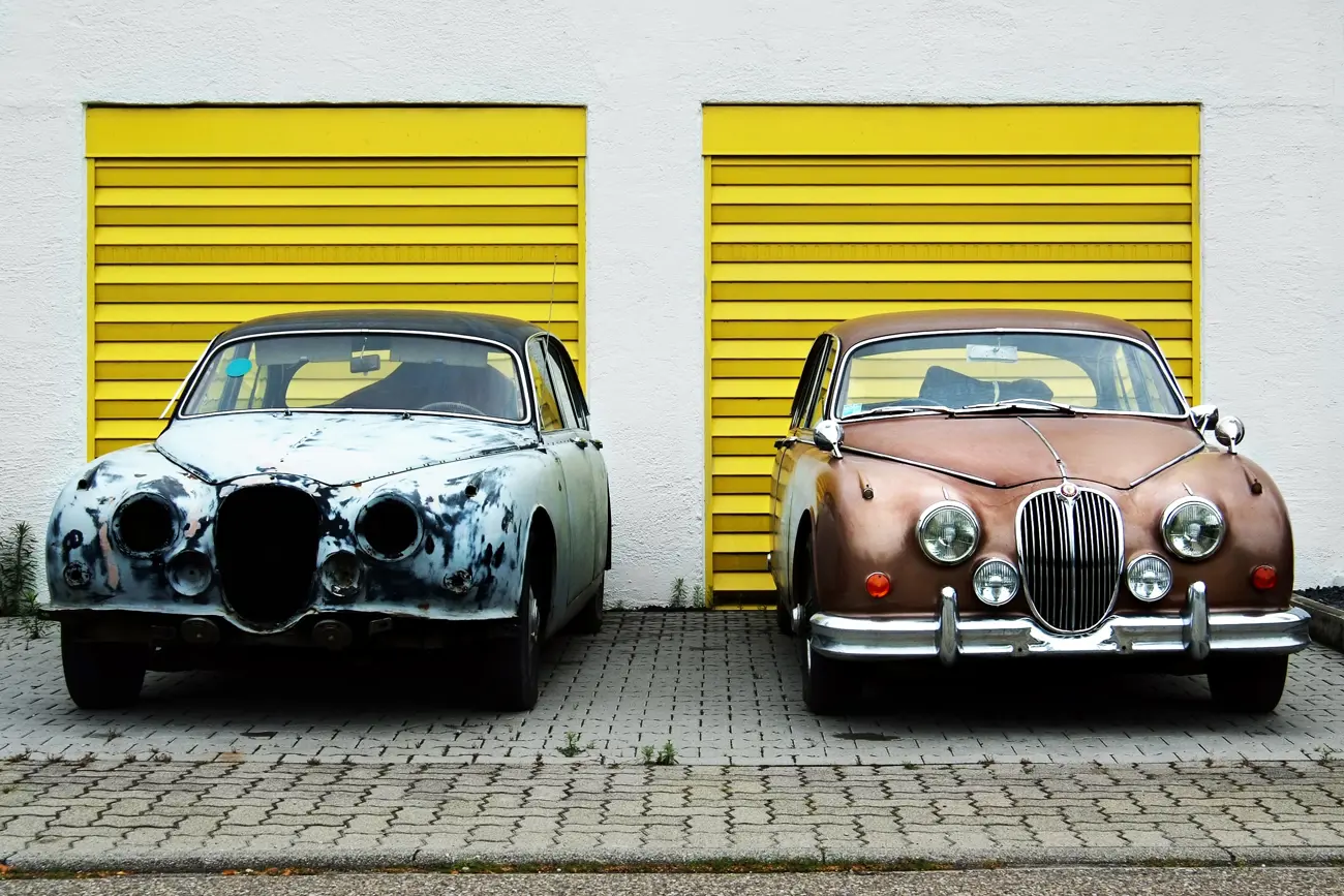 A classic car in rough shape next to a fully restored classic car of the same model